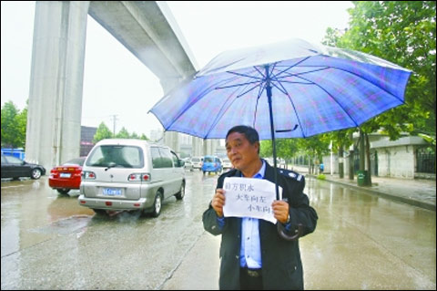 解放大道京广铁路涵洞渍水，双向交通严重拥堵，相关工作人员手持交通指示牌在暴雨中疏导交通。