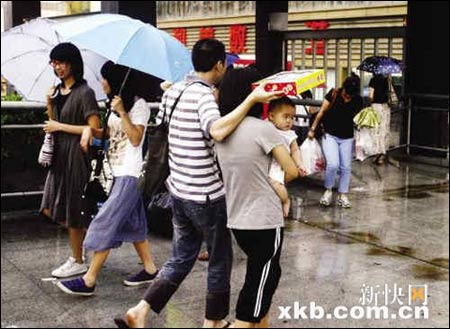 昨日下午，广州突降大雨，一名父亲在雨中用盒子为孩子挡雨。