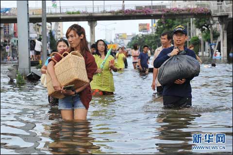 10月30日，在泰国首都曼谷的吞武里地区，人们在被洪水淹没的街道上涉水前行。泰国内政部防灾减灾厅30日通报，截至29日，持续三个月的洪灾造成泰国全国381人遇难，2人失踪。 新华社发（拉亨摄）