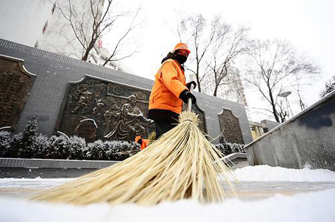 9日青海西宁出现降雪，图为一名环卫工人在西宁市街头扫雪